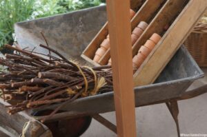 wheelbarrow, clay pots, bundle of sticks, garden sundries