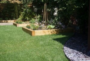 new turf lawn and raised vegetable beds, slate seating area, wooden raised beds around patio, family friendly garden